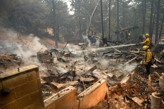 Firefighters hose down hot spots on a fire-ravaged property while battling the Bridge Fire, Wednesday, Sept. 11, 2024, in Wrightwood, Calif. (AP Photo/Eric Thayer)