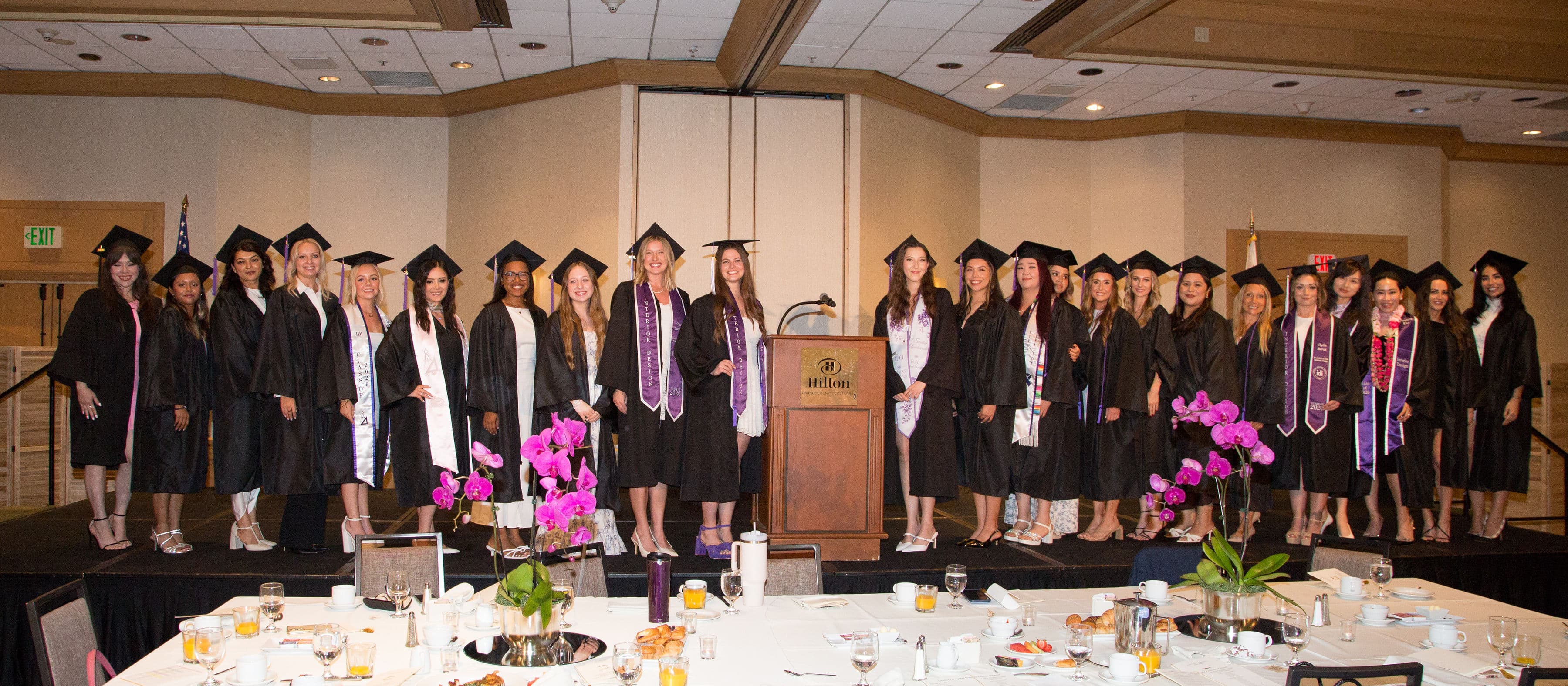The Interior Designers Institute Class of 2026 in caps and gowns on stage at the Hilton Orange County/Costa Mesa